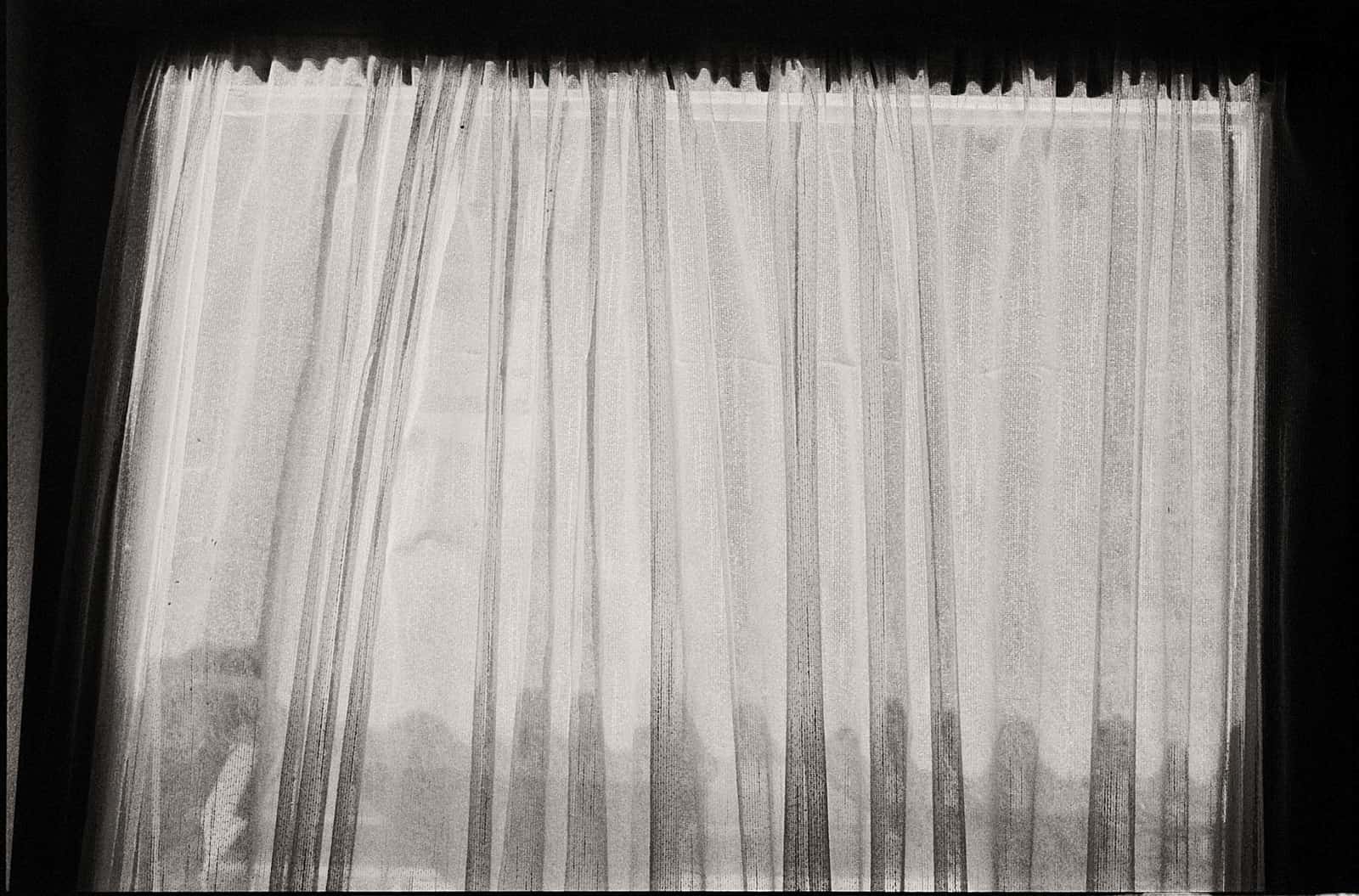 A sheer curtain layered in front of a heavier panel at a window