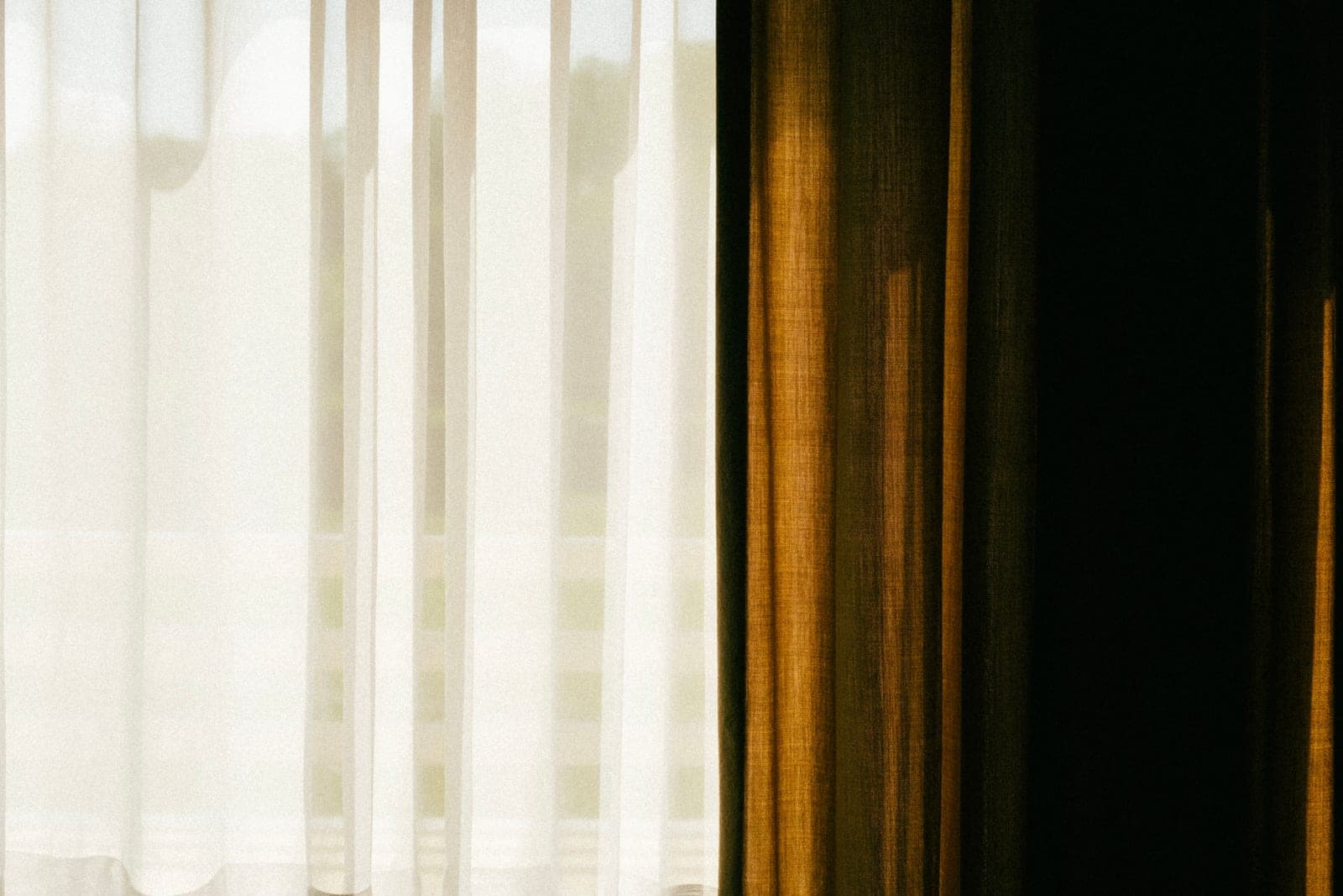 Daylight showing at the edge of a curtain against a window frame