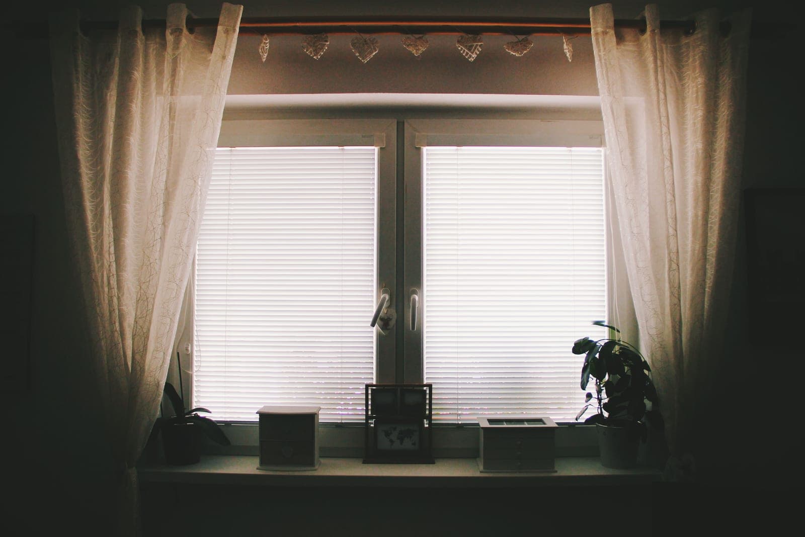 A window with curtains layered over a slatted blind
