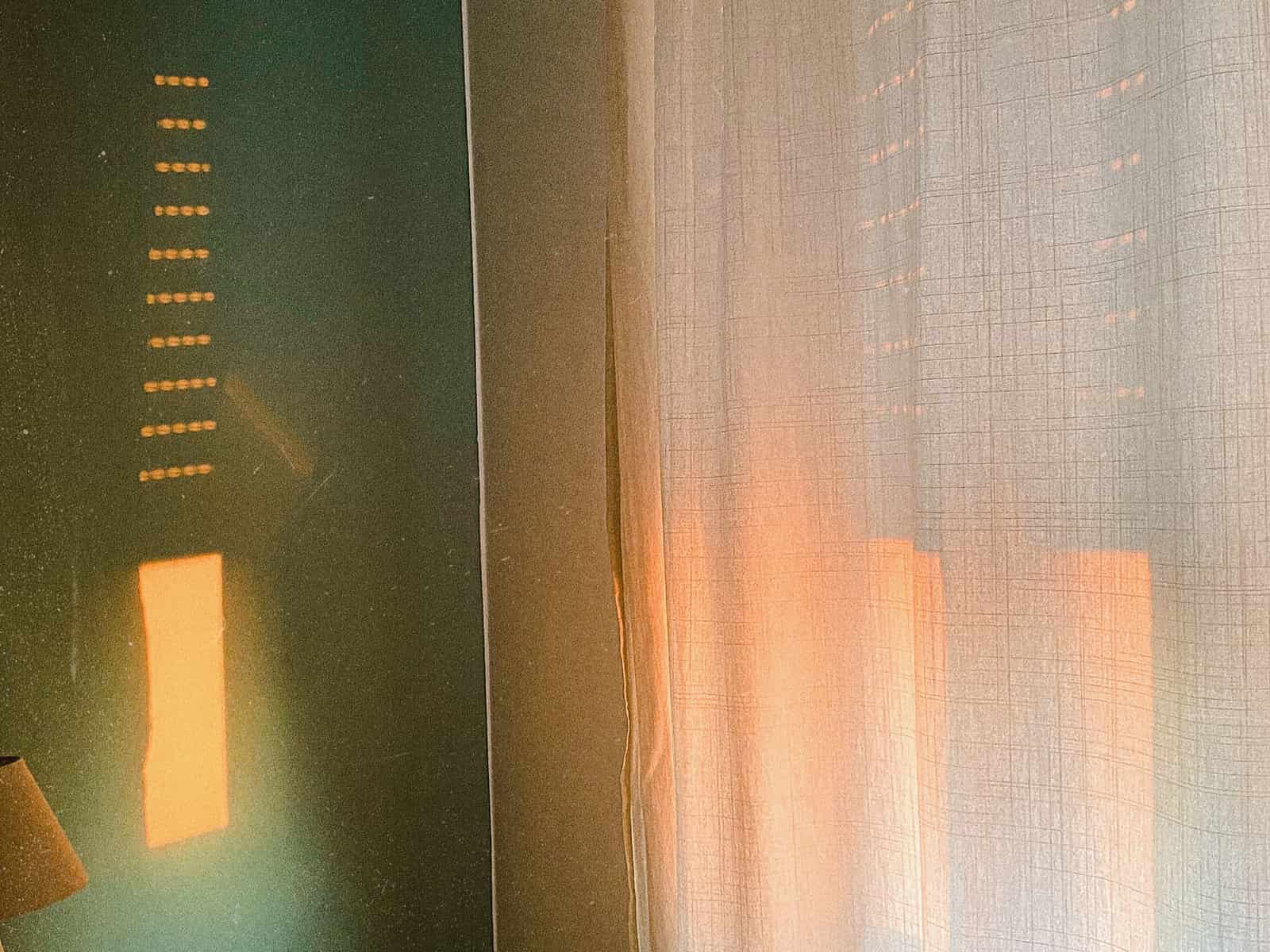 Strong summer sun falling on a window with curtains partly drawn