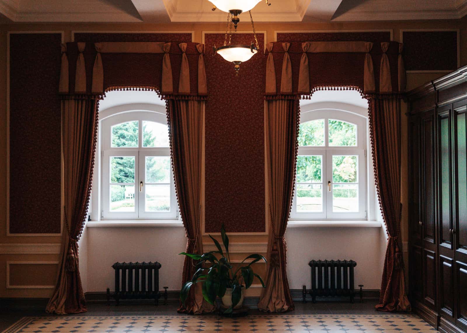 A radiator beneath a window with curtains hanging beside it