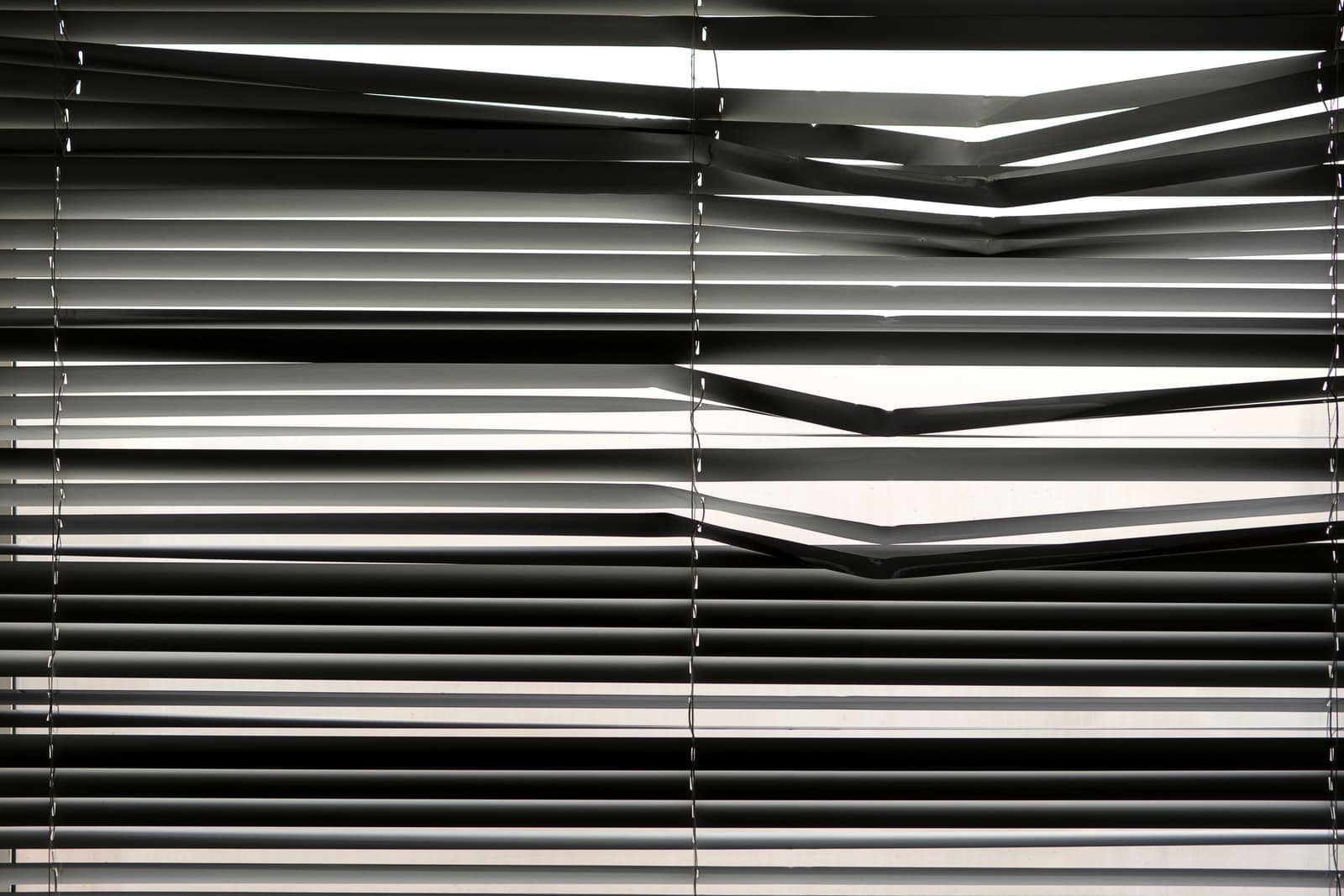 A roller shade partly lowered over a bright window in a modern room