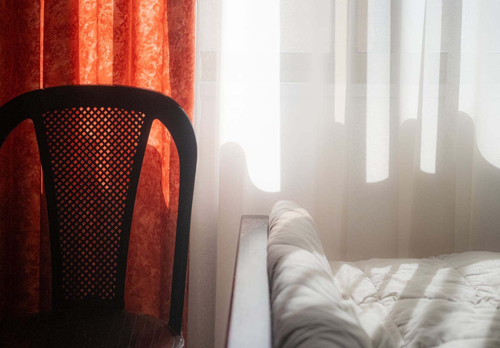 A bedroom in near-darkness with heavy curtains drawn against early morning light