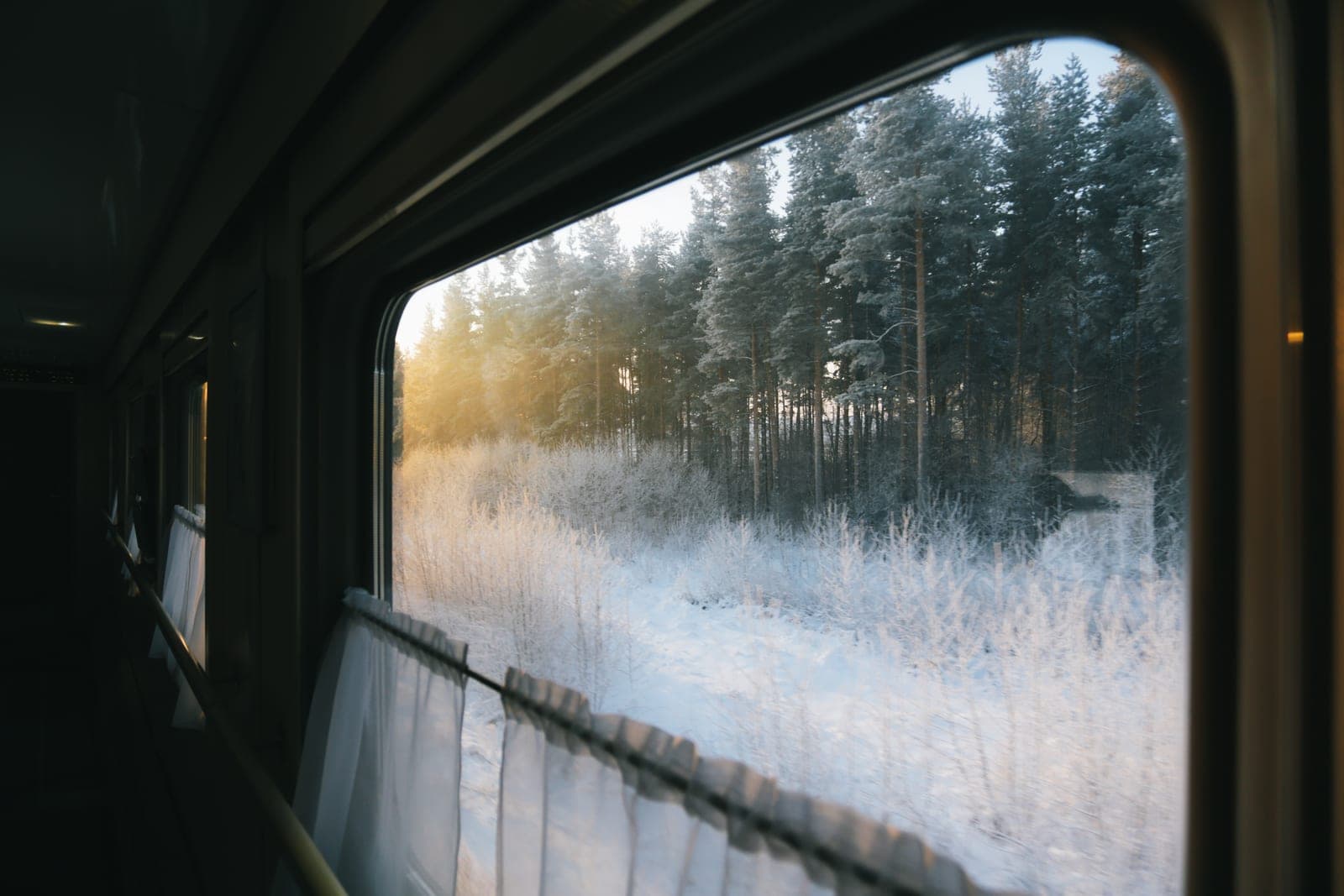 A frosted winter window with a heavy curtain pulled back beside it