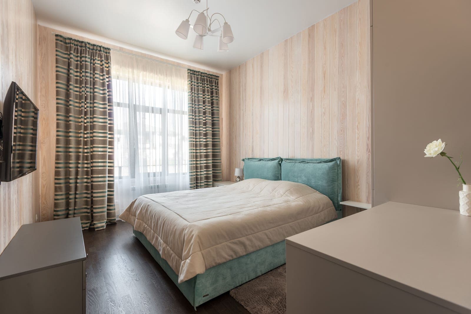 A small rental apartment window with simple curtains and plain white walls