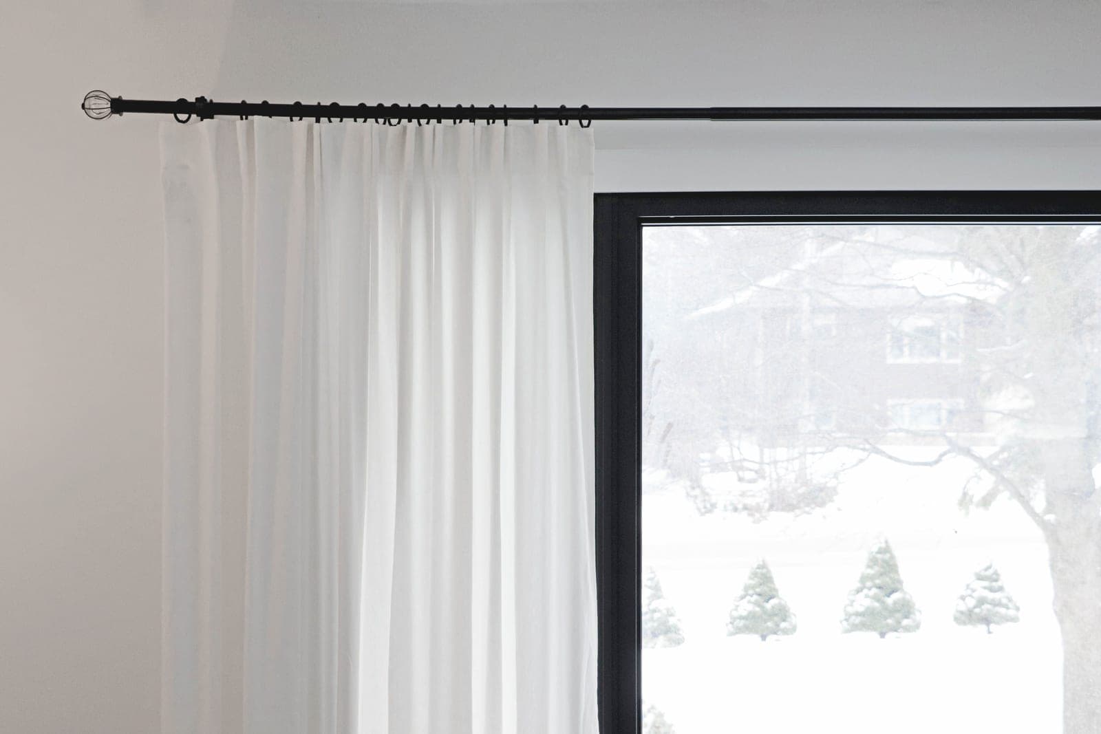 A curtain rod bracket mounted on the wall above a window frame