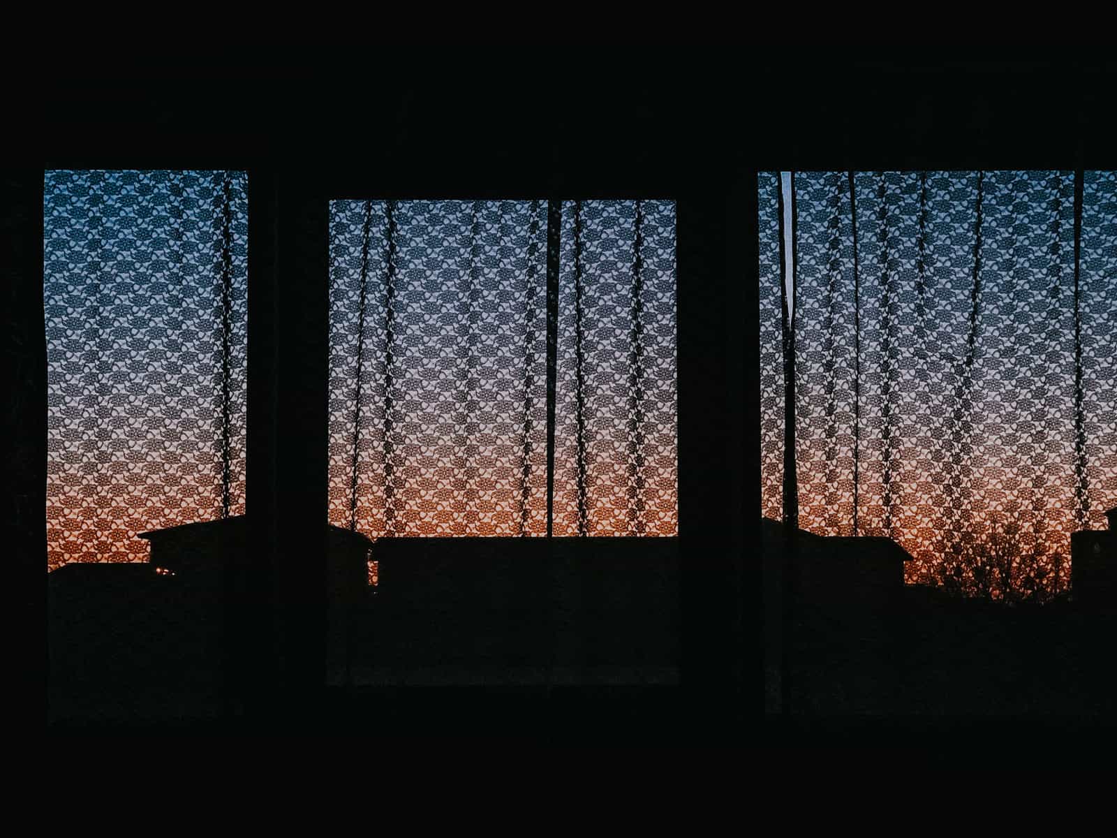 Closed curtains across an apartment window in the evening