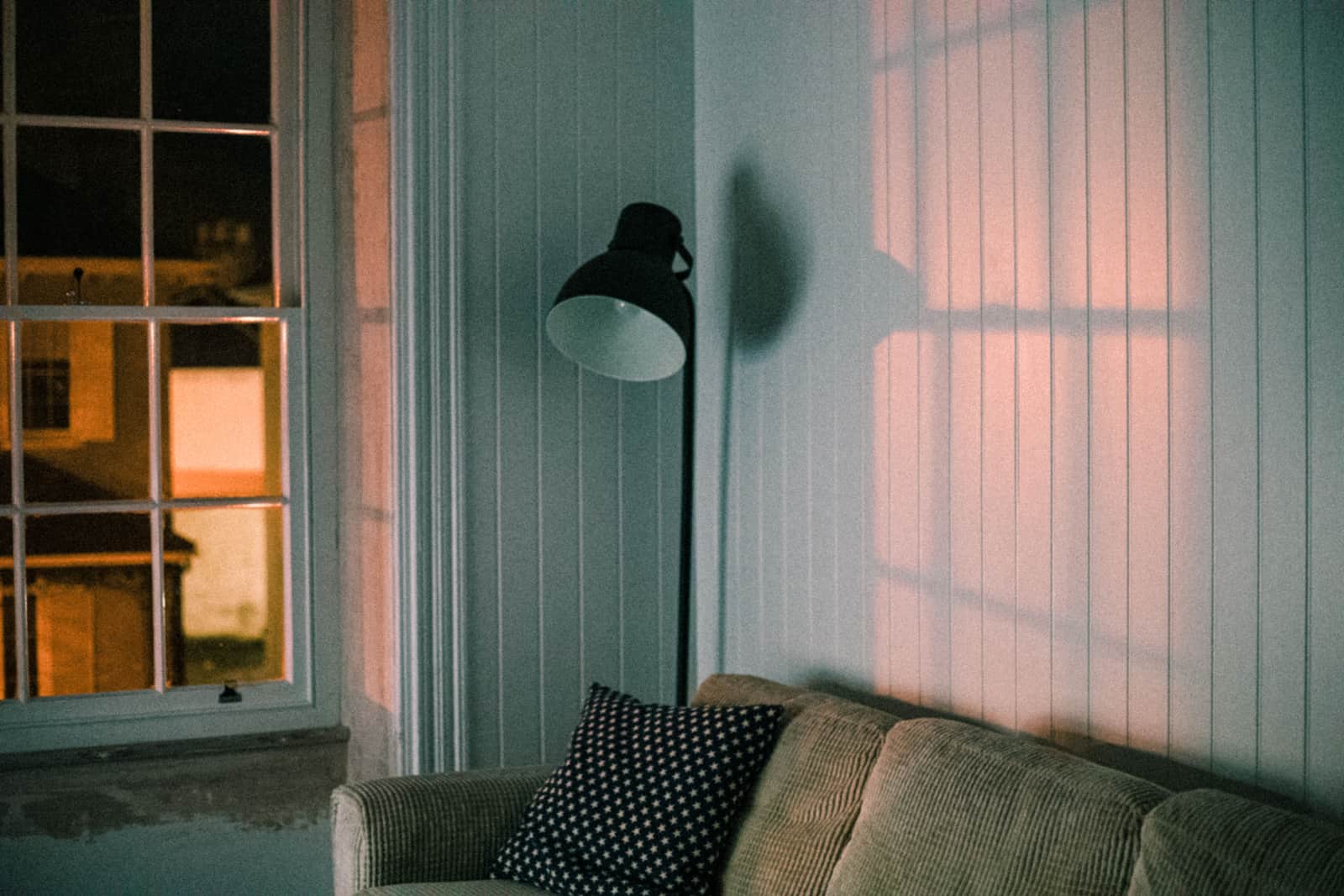 A living room window at dusk with lamps lit inside