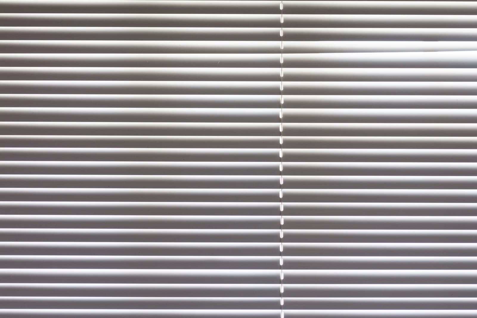 Close-up of horizontal blind slats angled against daylight