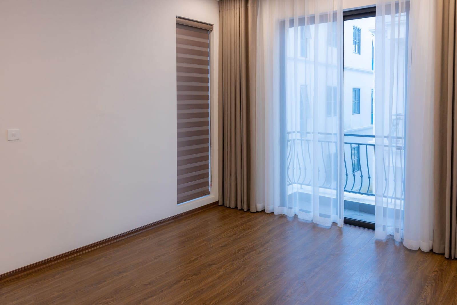A plain rental living room window with bare walls