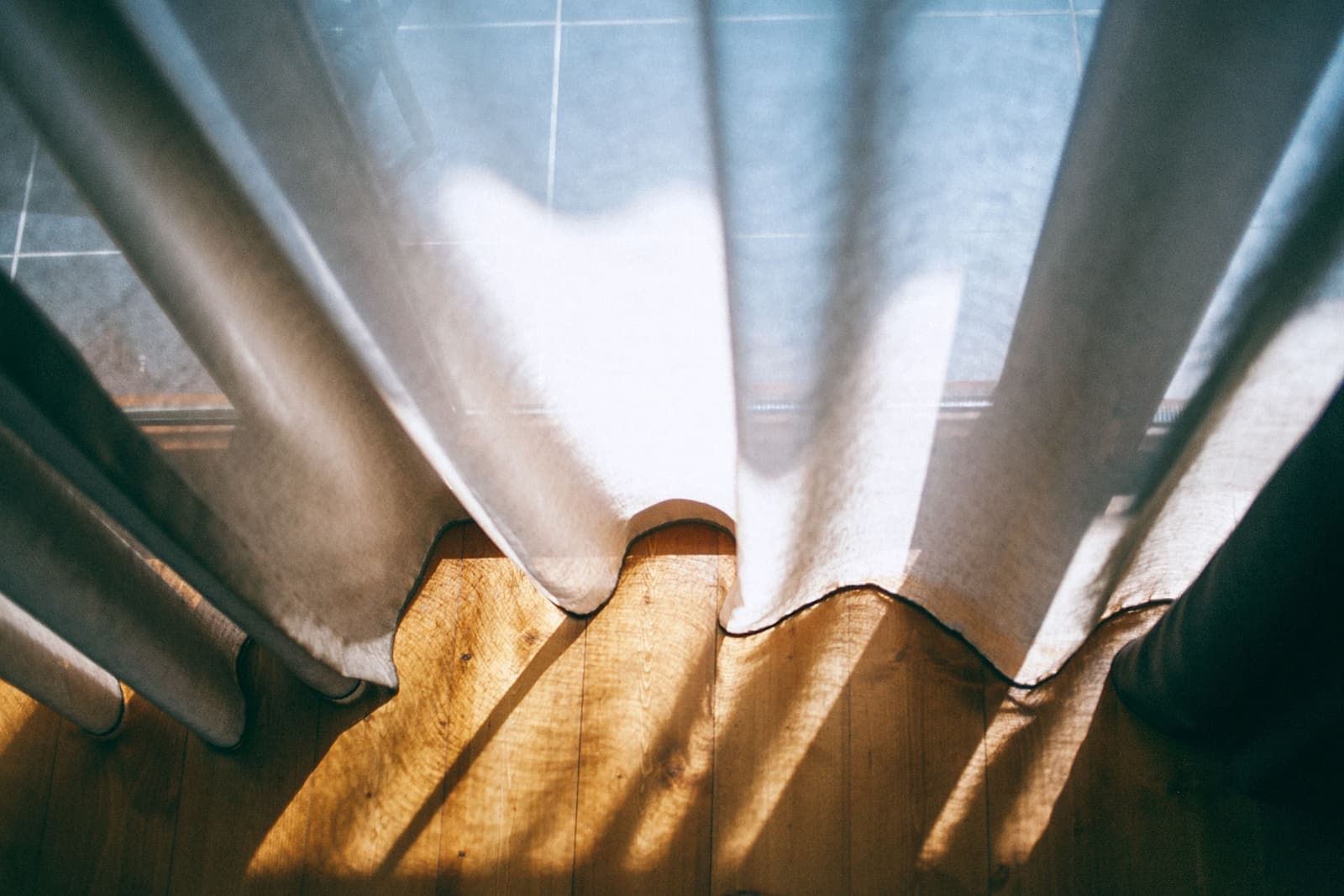 Floor-length curtains reaching the floor beside a window
