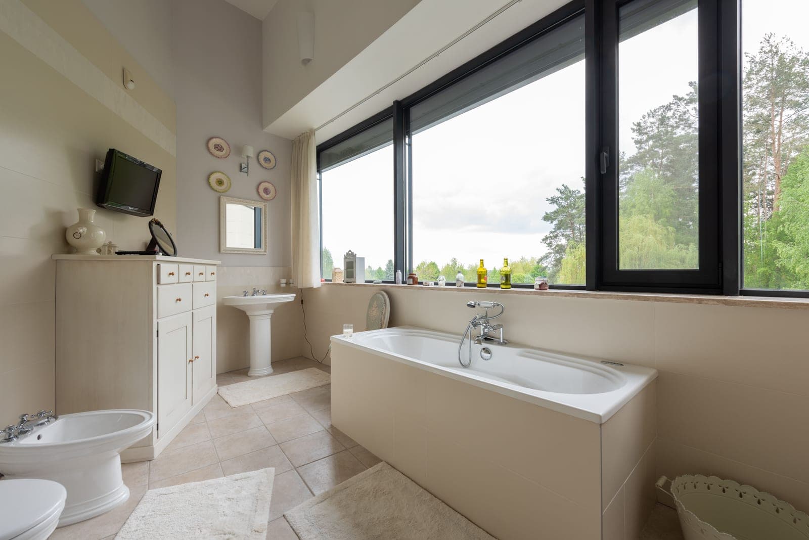 A bathroom window letting in natural light beside a bathtub