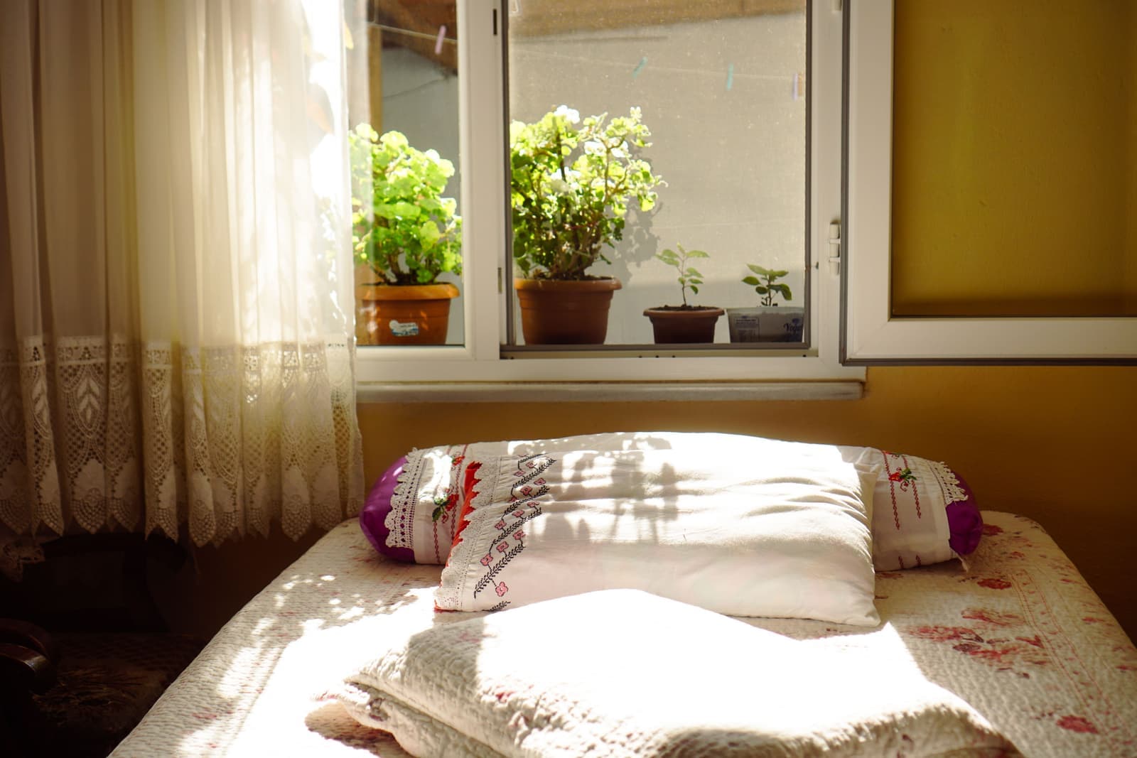 A calm bedroom with soft curtains at the window in morning light