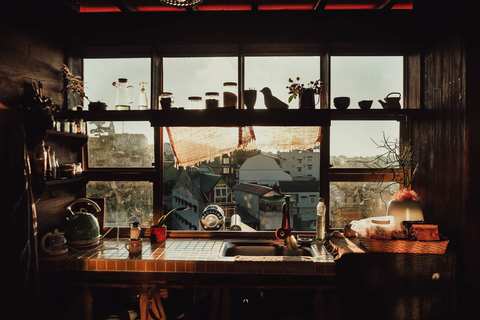 A kitchen window above a sink with daylight and plants on the sill